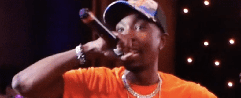 Performer singing passionately on stage with microphone.